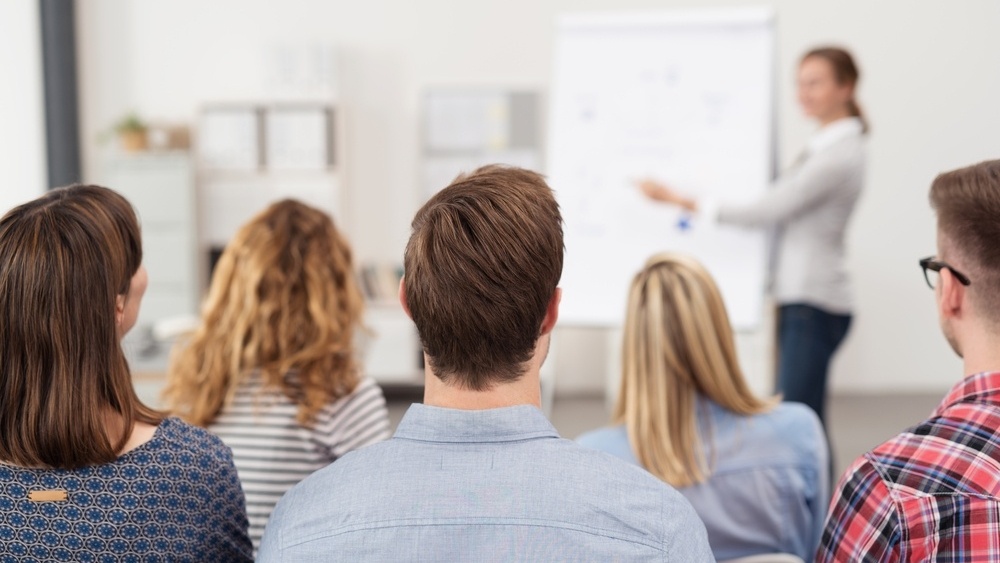 Rear View of Young Office Workers in Casual Outfits Listening to a Top Manager Explaining Something Using Illustrations.-452843-edited